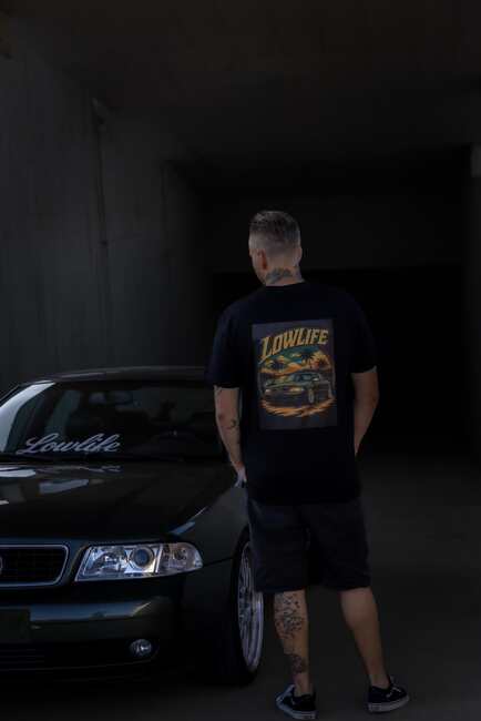 Schwarzes Lowlife Shirt mit Sunset-Motiv neben einem Audi